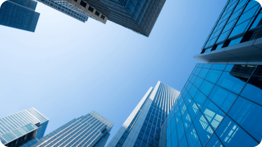 Upward view of glass skyscrapers against a clear blue sky, representing corporate business and urban growth.