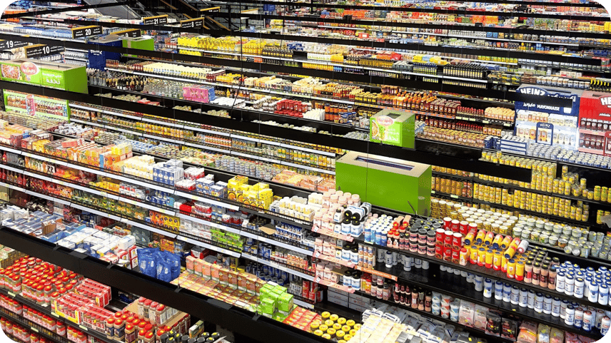 Supermarket aisle with fully stocked shelves of groceries and numbered aisle signs.
