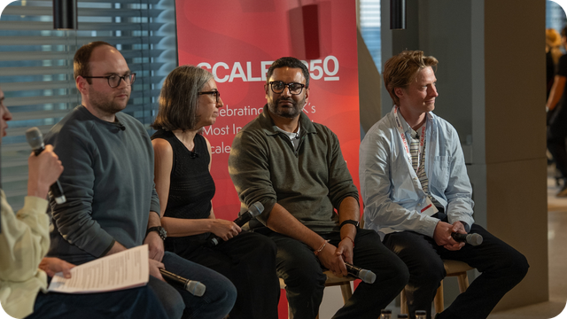 Two colleagues reviewing something on a laptop, one holding a coffee mug, in a light green office space. (2)